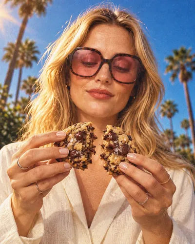 Une jeune femme rompt un cookie maison au chocolat de Woody's Factory, sous les palmiers
