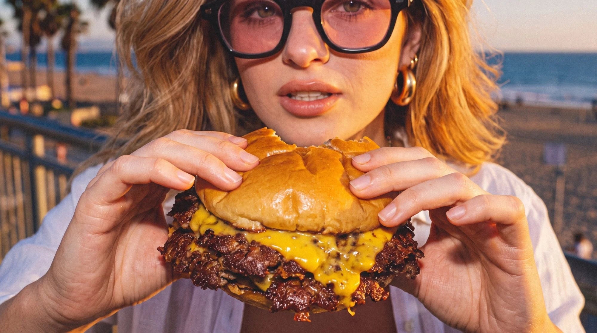 Une cliente savoure un smash burger Woody's au coucher du soleil, sur la plage