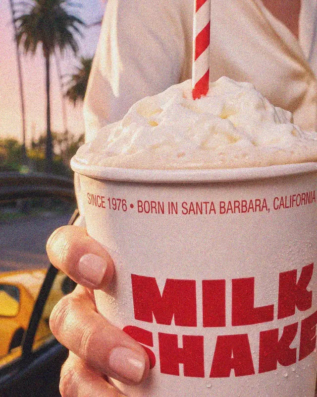 Gros plan sur le milkshake The Real Shake, crème glacée et chantilly, paille rayée, dans le gobelet Woody's Factory