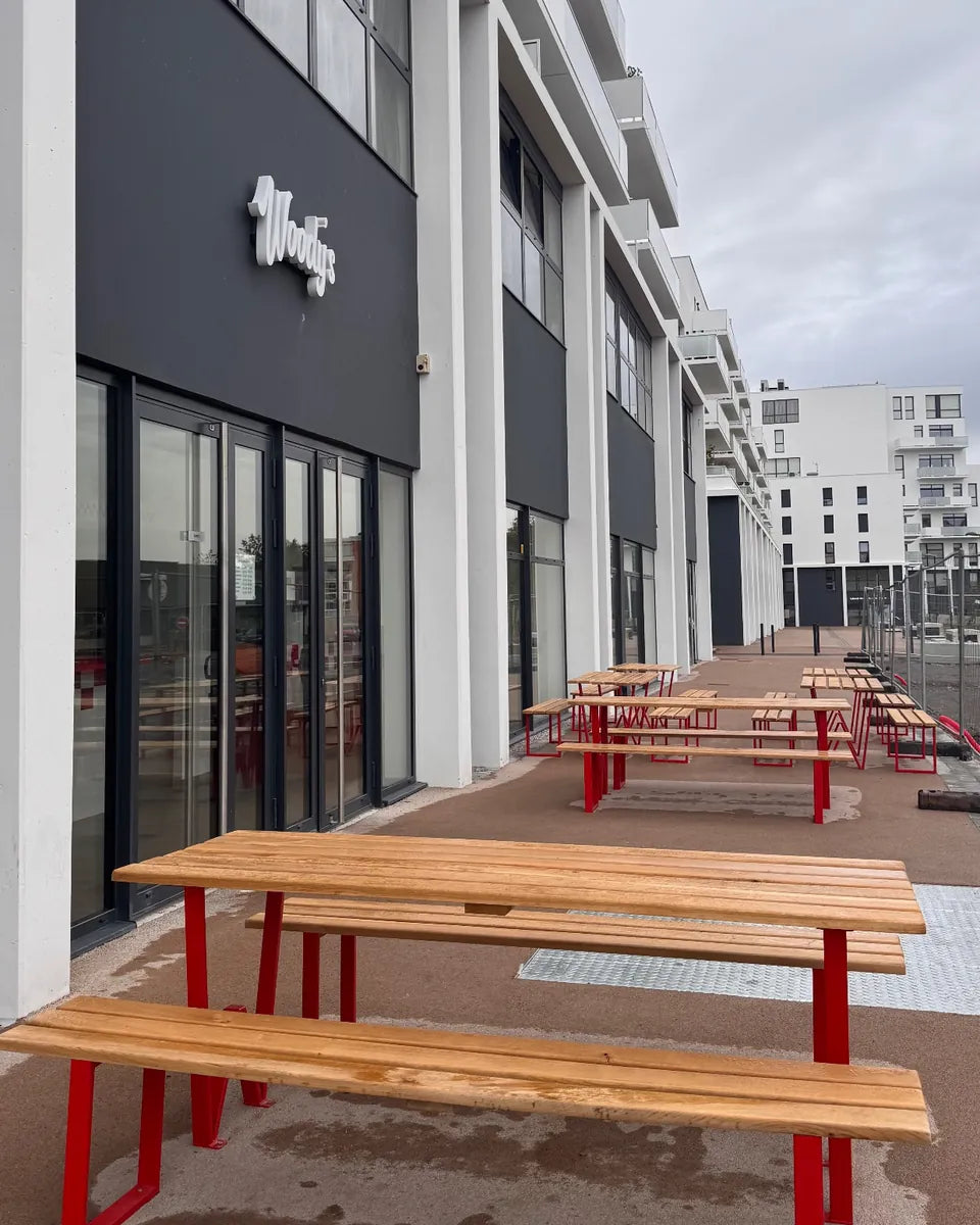 Terrasse de Woody's Factory Lens : tables et bancs en bois aux pieds rouges, avenue André Delelis