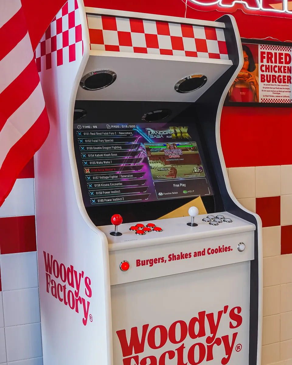 Borne d'arcade Woody's Factory à Douai : grande borne blanche et rouge, damier, joysticks, sous le néon California