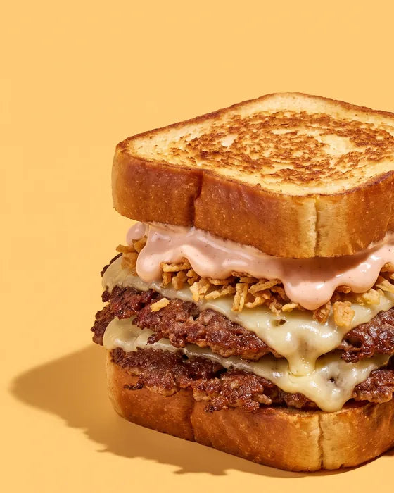 Burger The Melt de Woody's Factory : brioche au beurre toastée, double steak smashé, emmental fondu, oignons frits et sauce maison