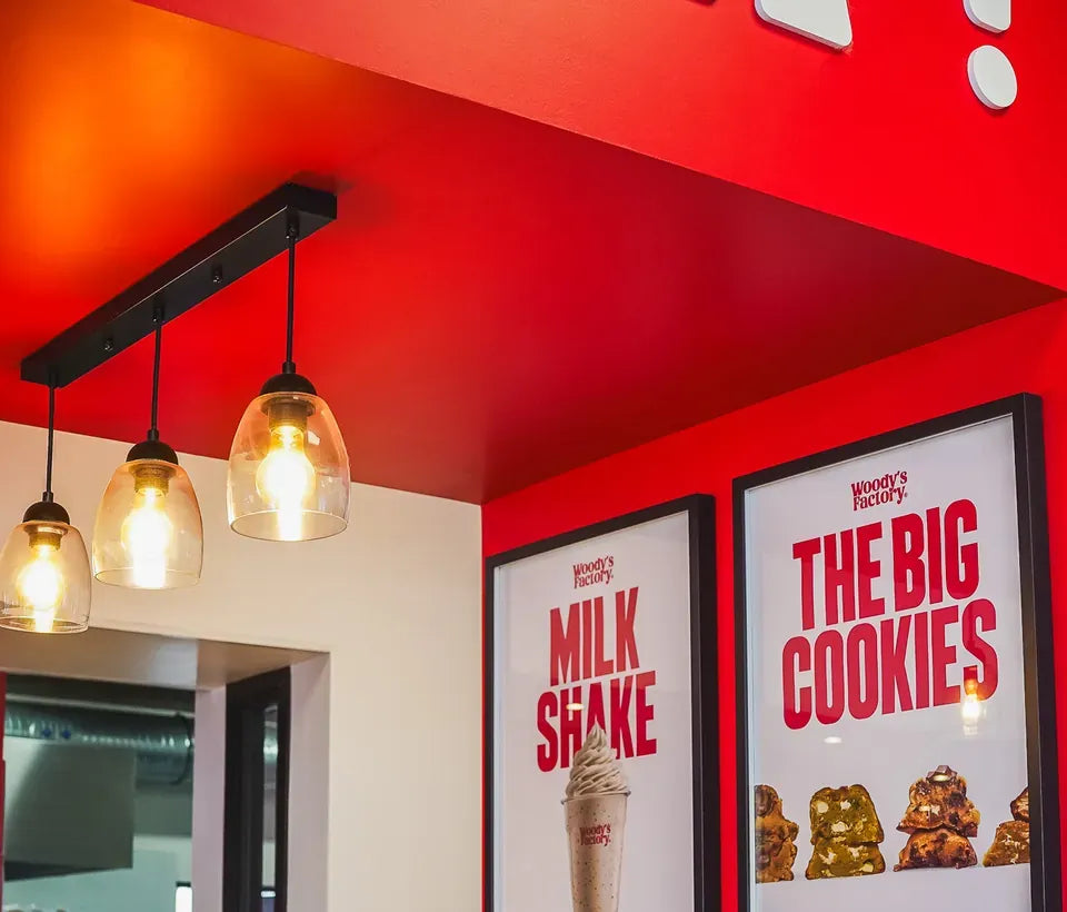 Le coin milkshakes et cookies de Woody's Factory Douai : affiches Milk Shake et The Big Cookies sur un mur rouge