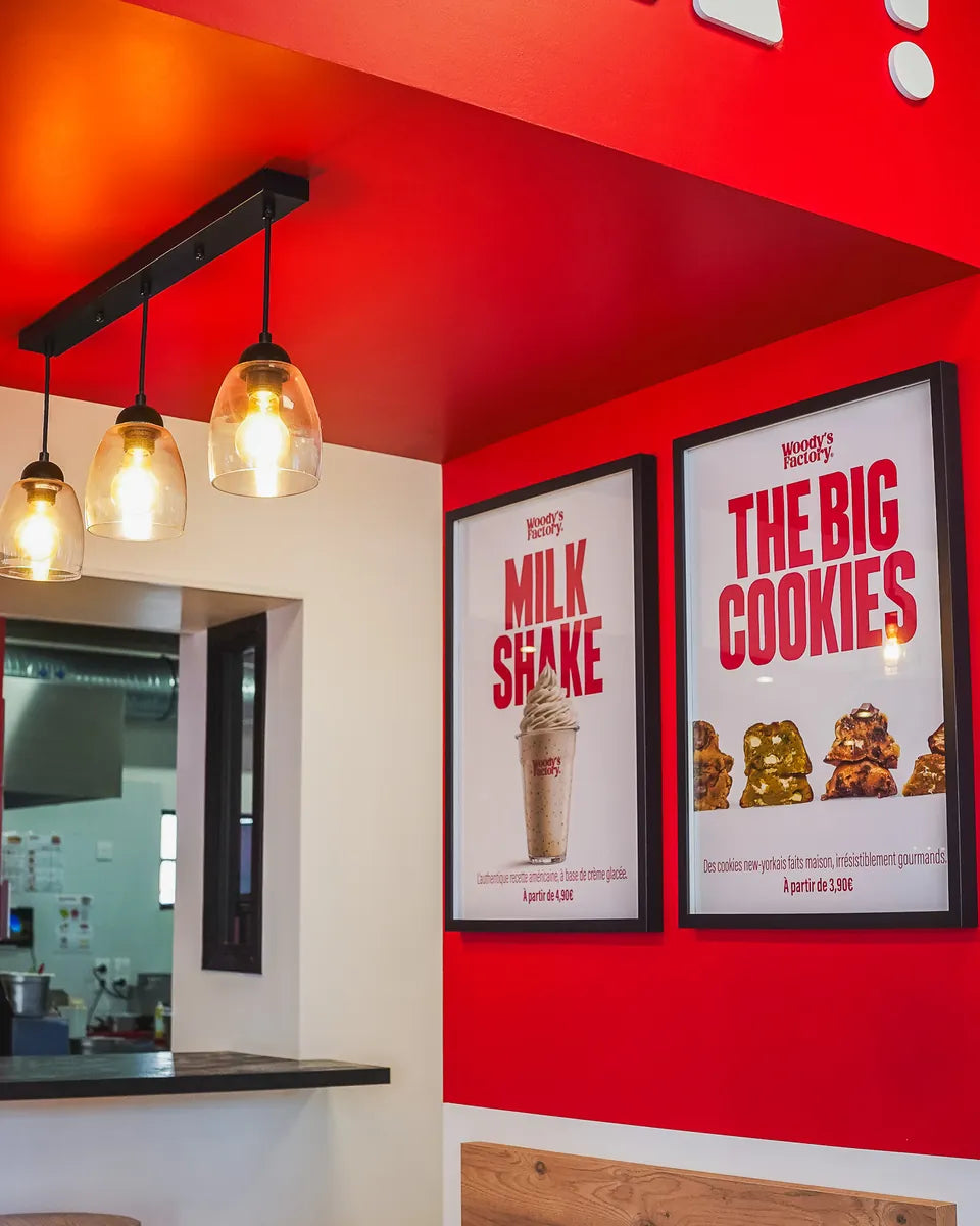 Coin bar de Woody's Factory Douai : affiches Milkshake et The Big Cookies, suspensions et tablette en bois