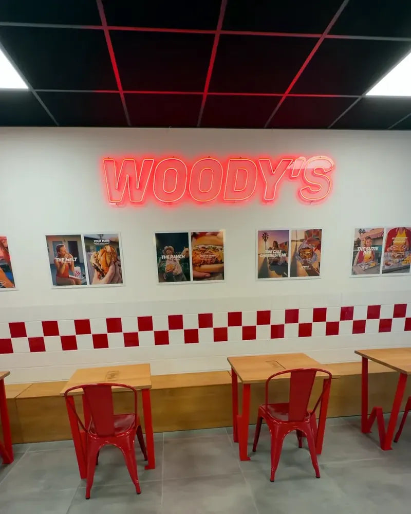 Grande salle de Woody's Factory Lens : néon Woody's, banquette et chaises rouges