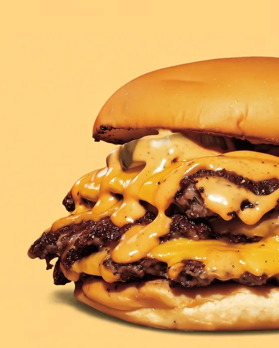 Smash burger The 1976 de Woody's Factory : double steak smashé, cheddar fondu, pickles et sauce, sur fond jaune