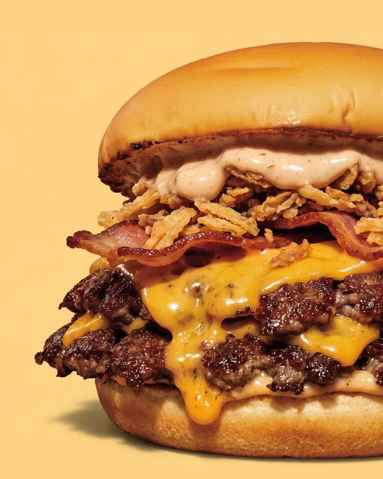 Smash burger The Trucker de Woody's Factory : double steak smashé, cheddar, bacon, oignons frits et sauce bacon