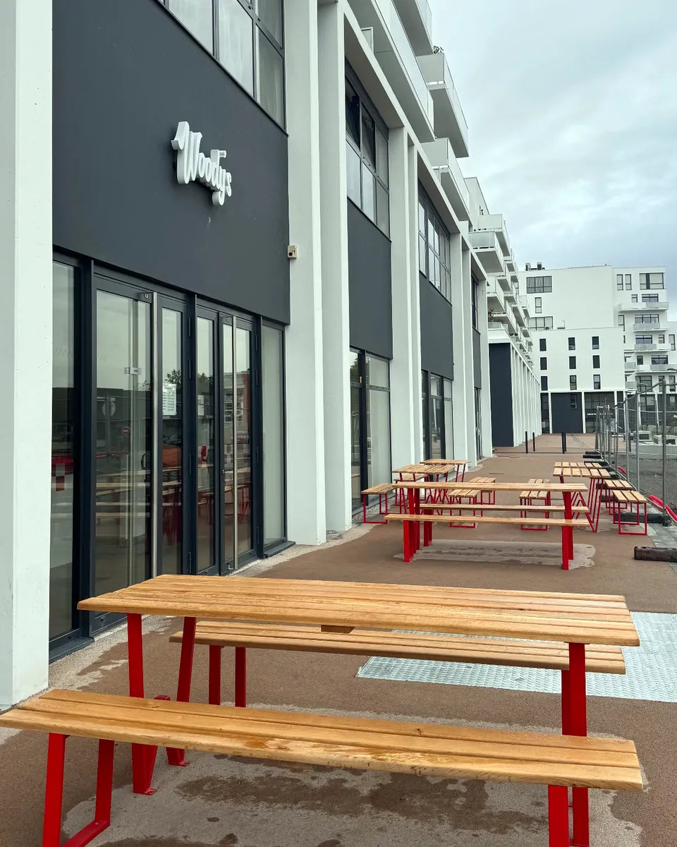 Terrasse de Woody's Lens : tables rouges en plein air